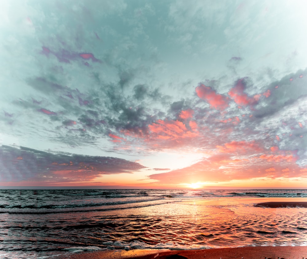 o sol está se pondo sobre o oceano na praia