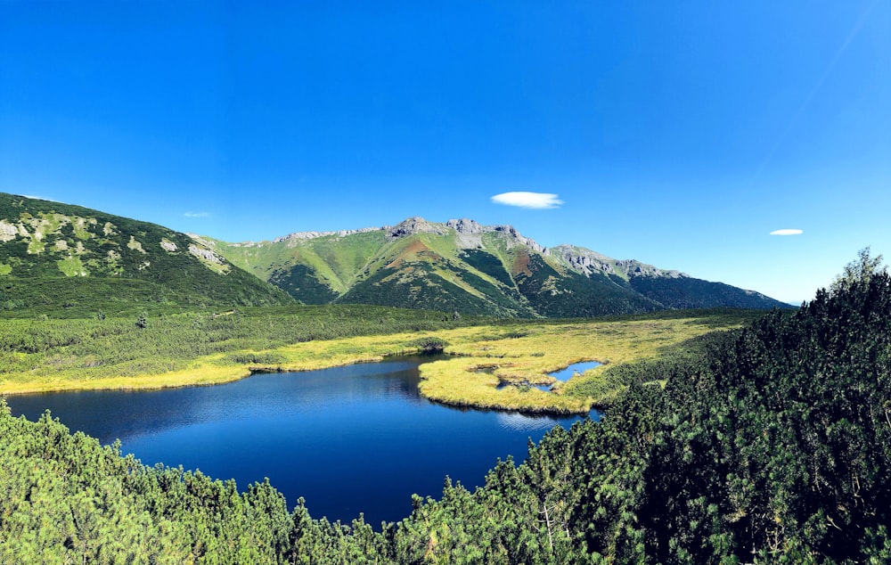 Montañas verdes cerca del lago bajo el cielo azul durante el día