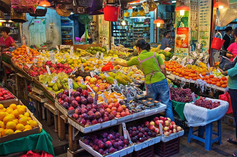 woman in yellow shirt standing in front of fruit stand