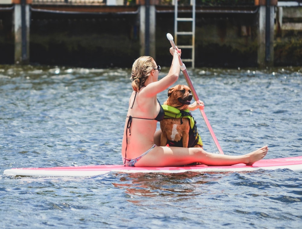 woman in green bikini riding on red and white surfboard during daytime