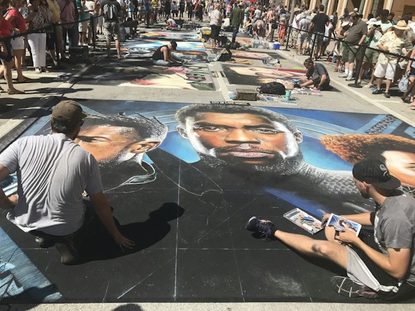 Two people talking in front of artwork displayed at a weekend outdoor arts event