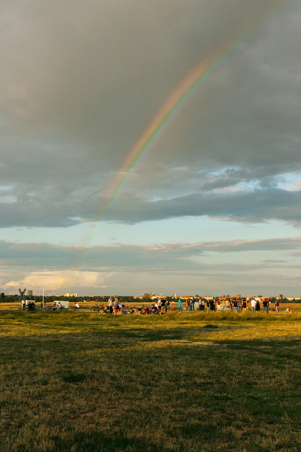 people on green grass field under rainbow
