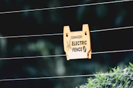 Electric fence installation in progress with bright orange warning signs visible.
