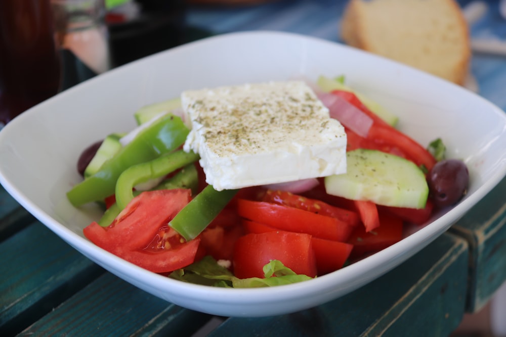 sliced tomato and green vegetable on white ceramic bowl