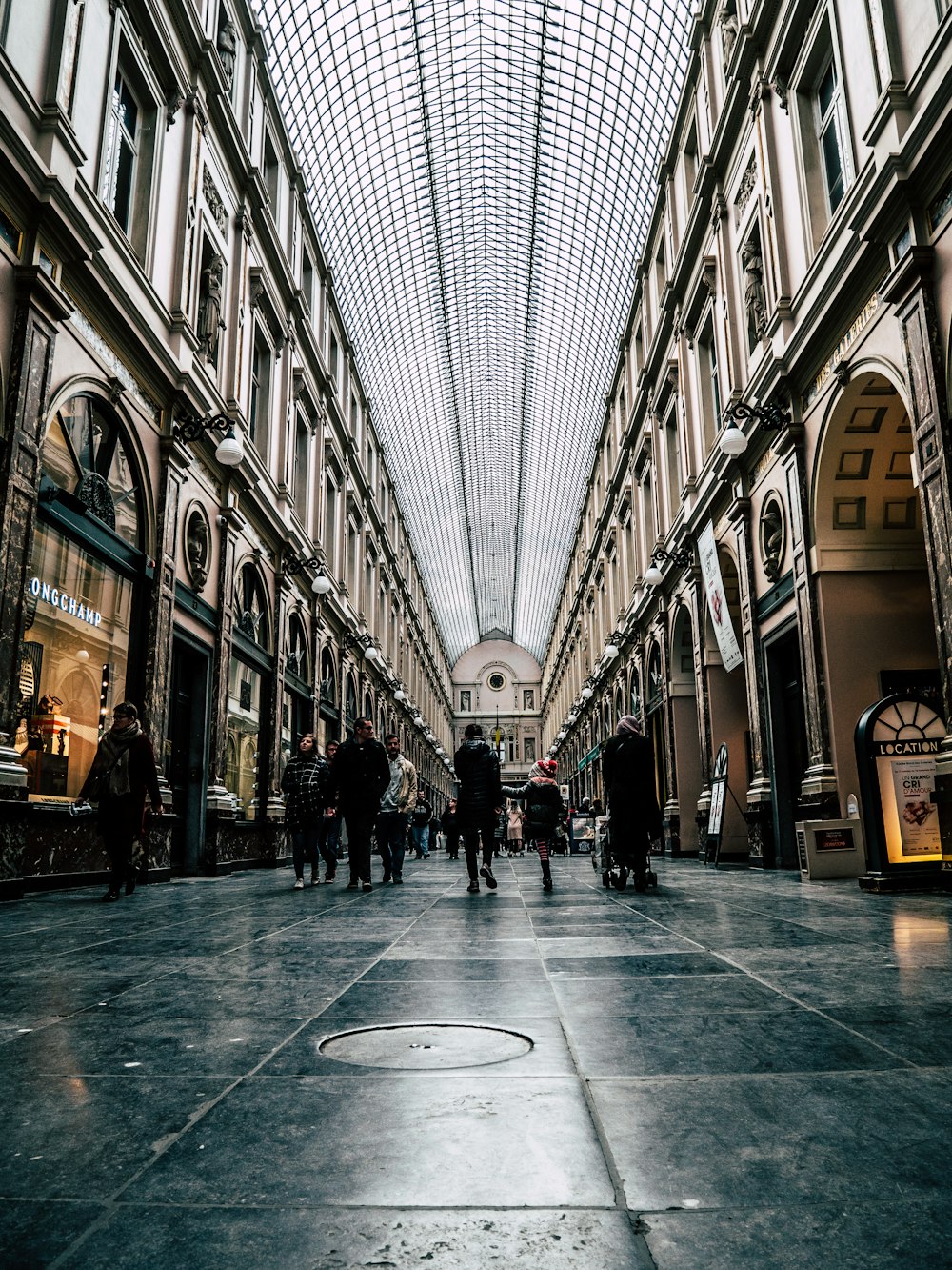 people walking on hallway between buildings during daytime