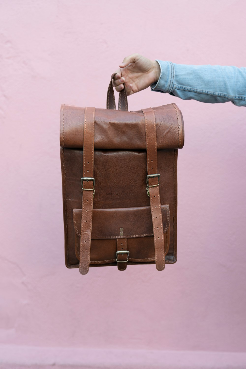 person in blue denim jeans holding brown leather handbag