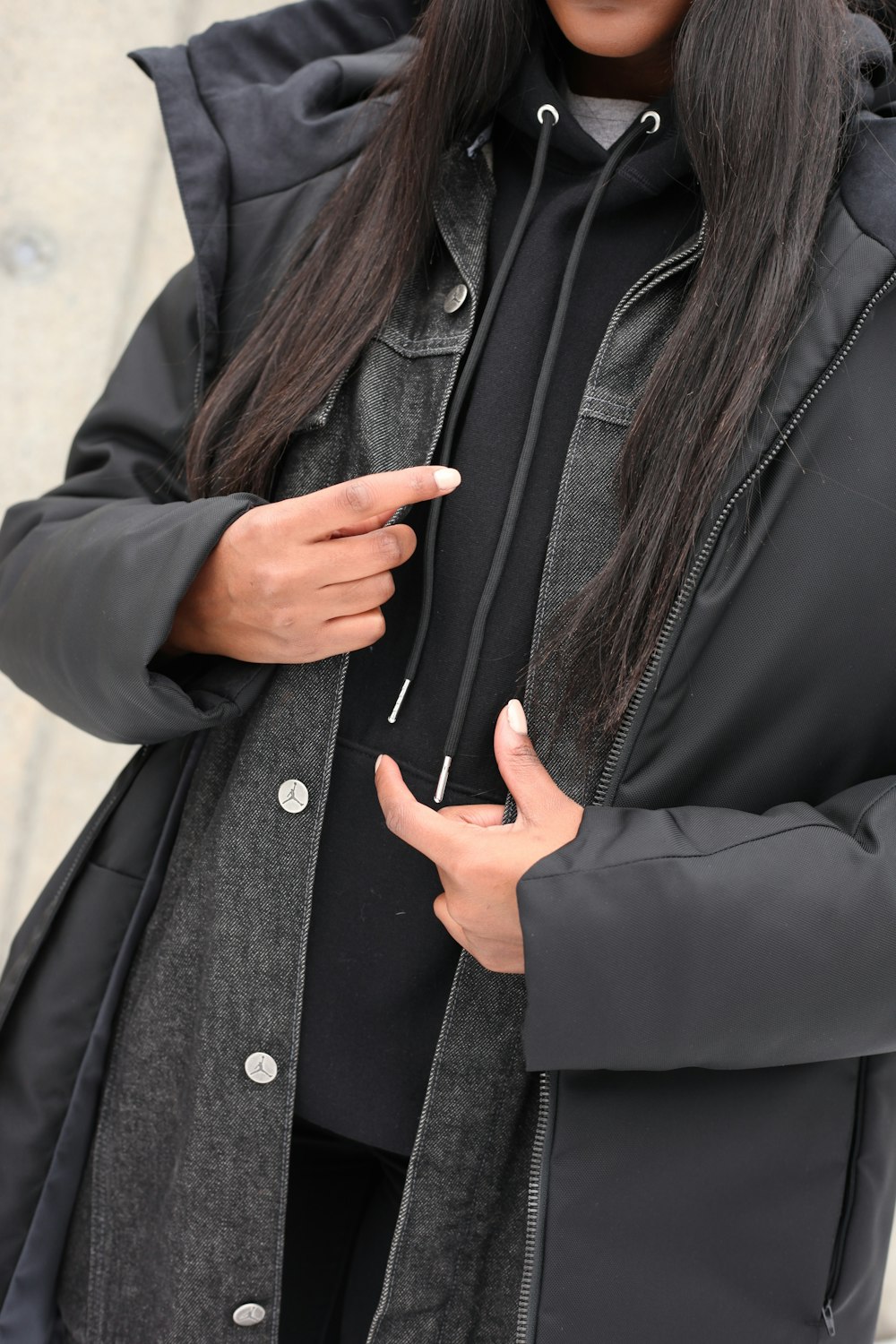 woman in black coat holding her chin