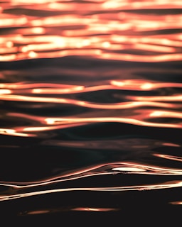 Abstract image of waves with a golden reflection, creating a visually appealing pattern with flowing lines and a smooth texture.