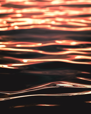 Abstract image of waves with a golden reflection, creating a visually appealing pattern with flowing lines and a smooth texture.