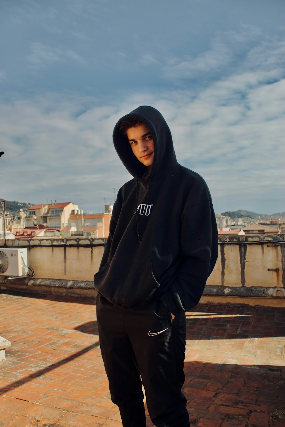 man in black hoodie standing on brown brick floor during daytime