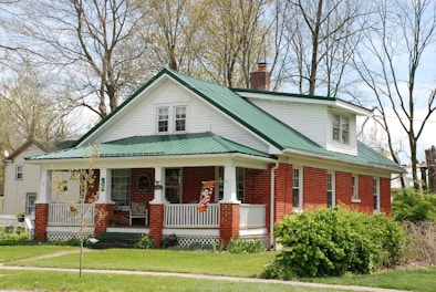 white and brown wooden house near green trees during daytime