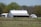 Farmer inspecting a newly built steel hangar with green fields in the background.
