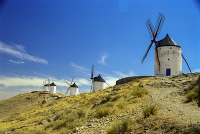 windmill on green grass field under blue sky during daytime