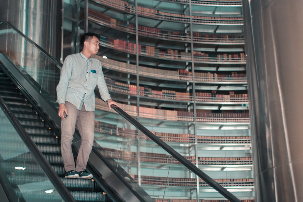 man in gray dress shirt and gray pants standing on black escalator