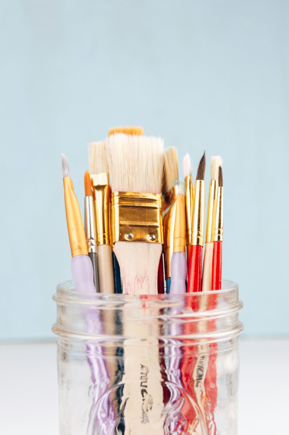 brown and red makeup brushes in clear glass jar