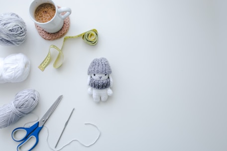 Flat lay of crochet tools and materials on a pastel blue background.