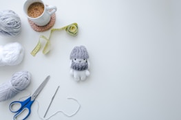 Minimalist flat lay of earth-toned yarn balls beside elegant crochet tools on a charcoal background.