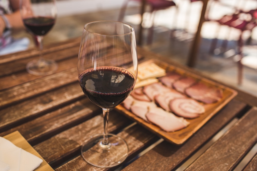 clear wine glass with red wine on brown wooden table