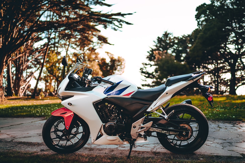 white and black sports bike parked on gray concrete pavement during daytime