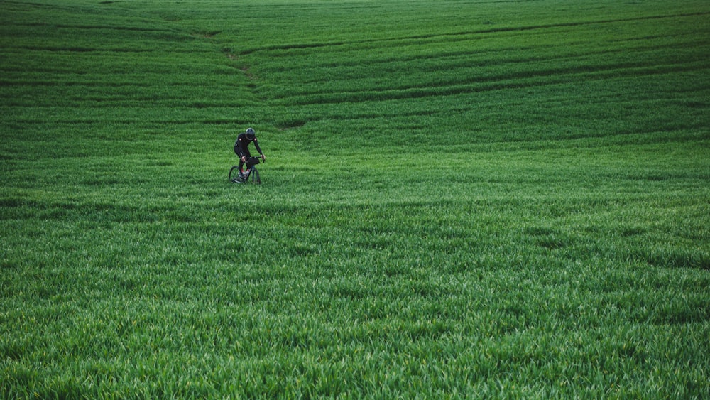 person in red jacket riding bicycle on green grass field during daytime