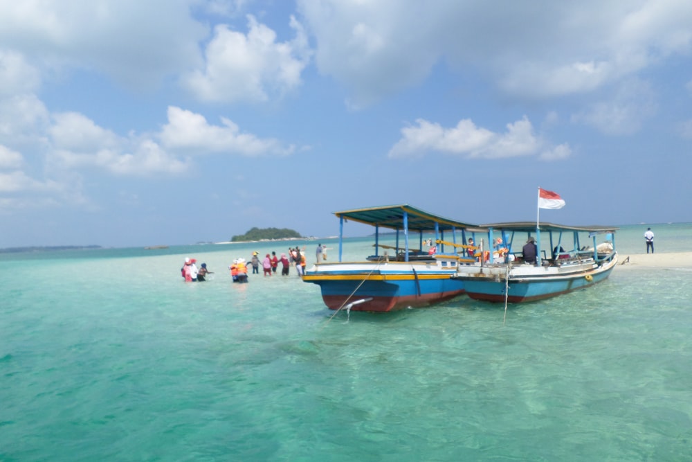 people on blue and yellow boat on sea under blue and white sky during daytime