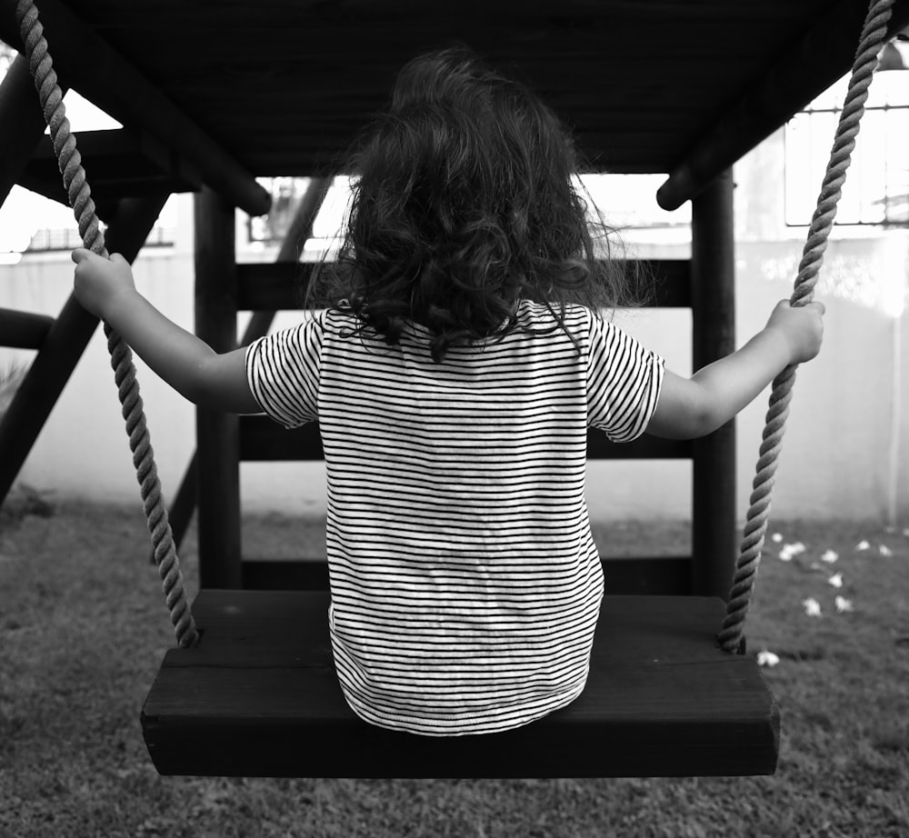 girl in white and black striped shirt sitting on swing