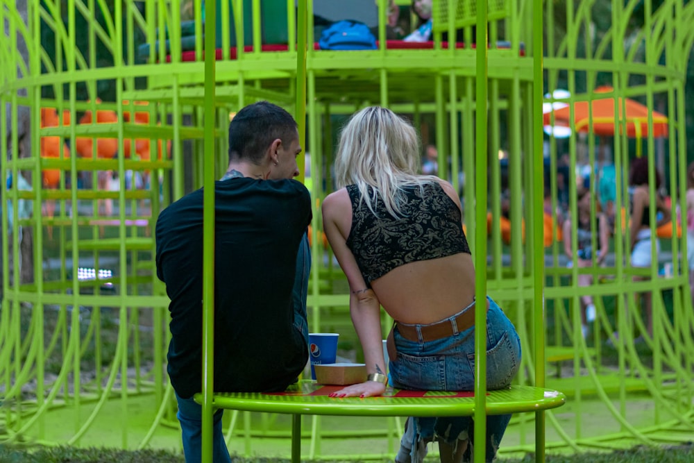 man and woman kissing on blue metal fence during daytime