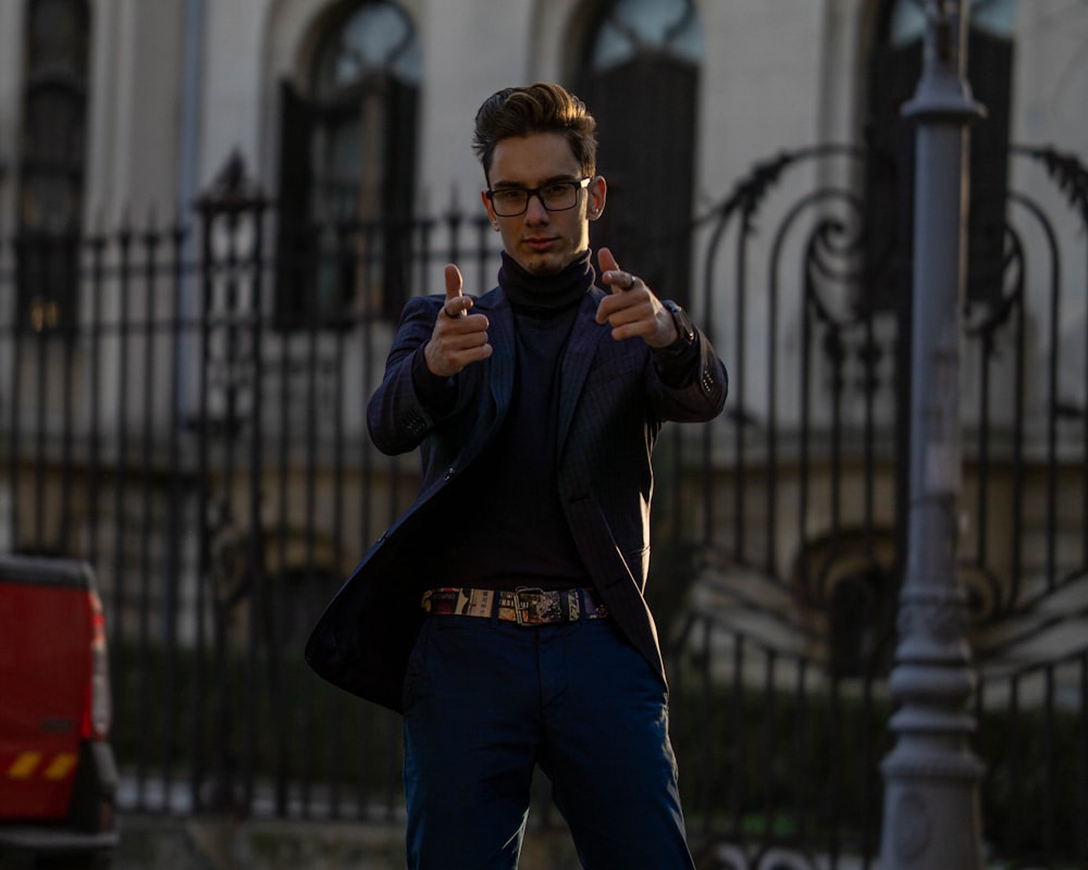 man in black jacket and blue denim jeans wearing eyeglasses