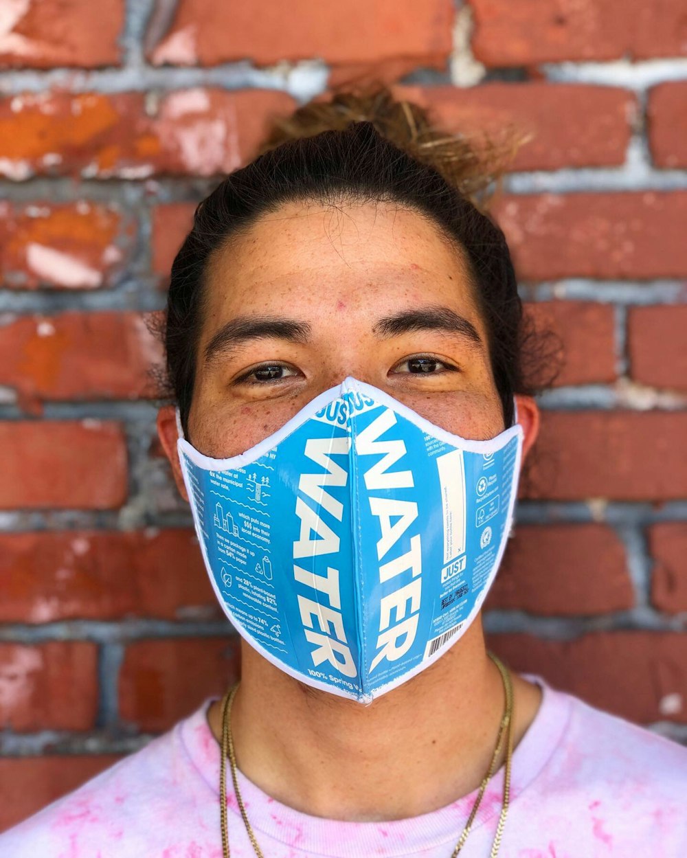 man in pink and white shirt with Just Water mask made out of recycled water bottles