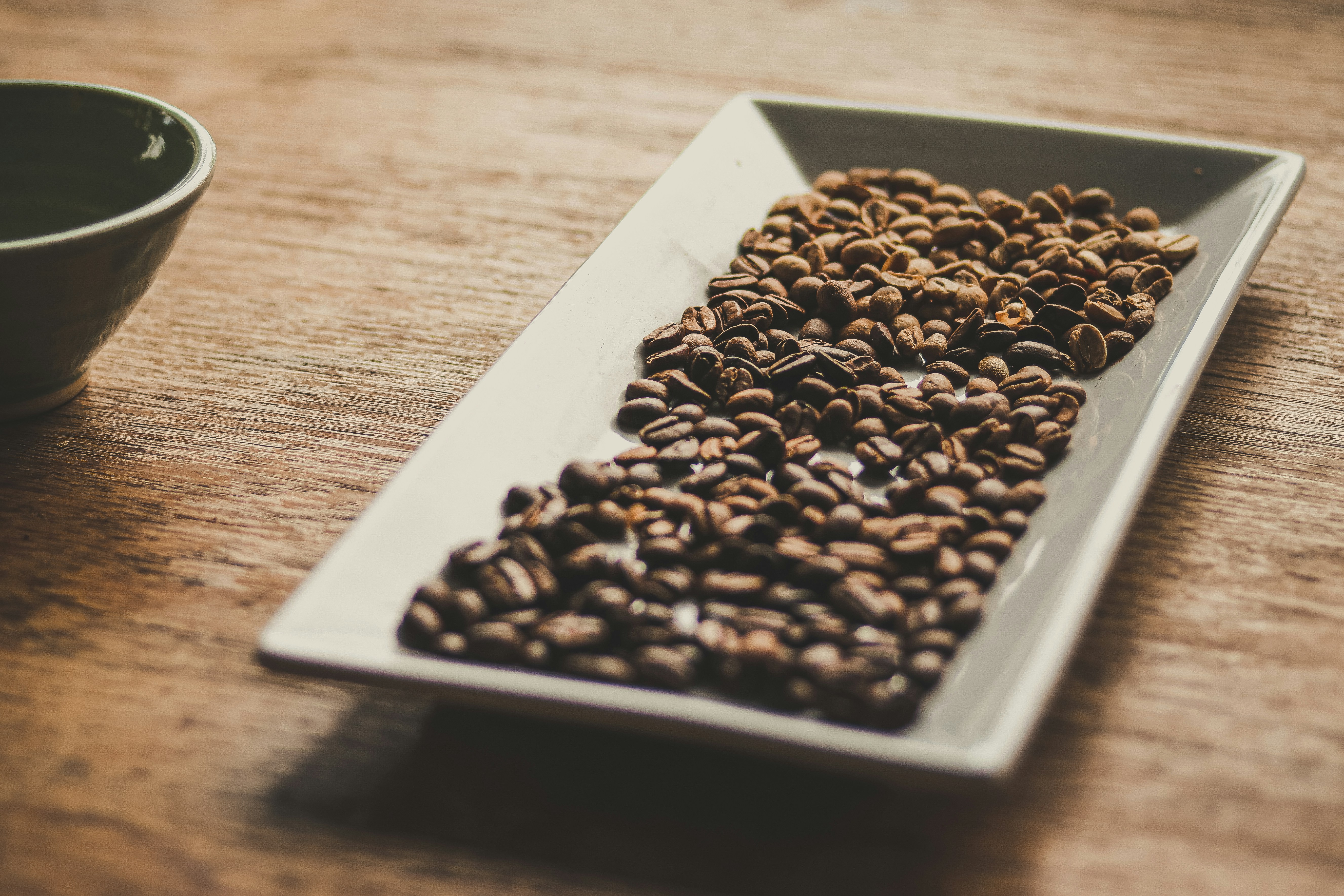 black and brown coffee beans on white ceramic tray