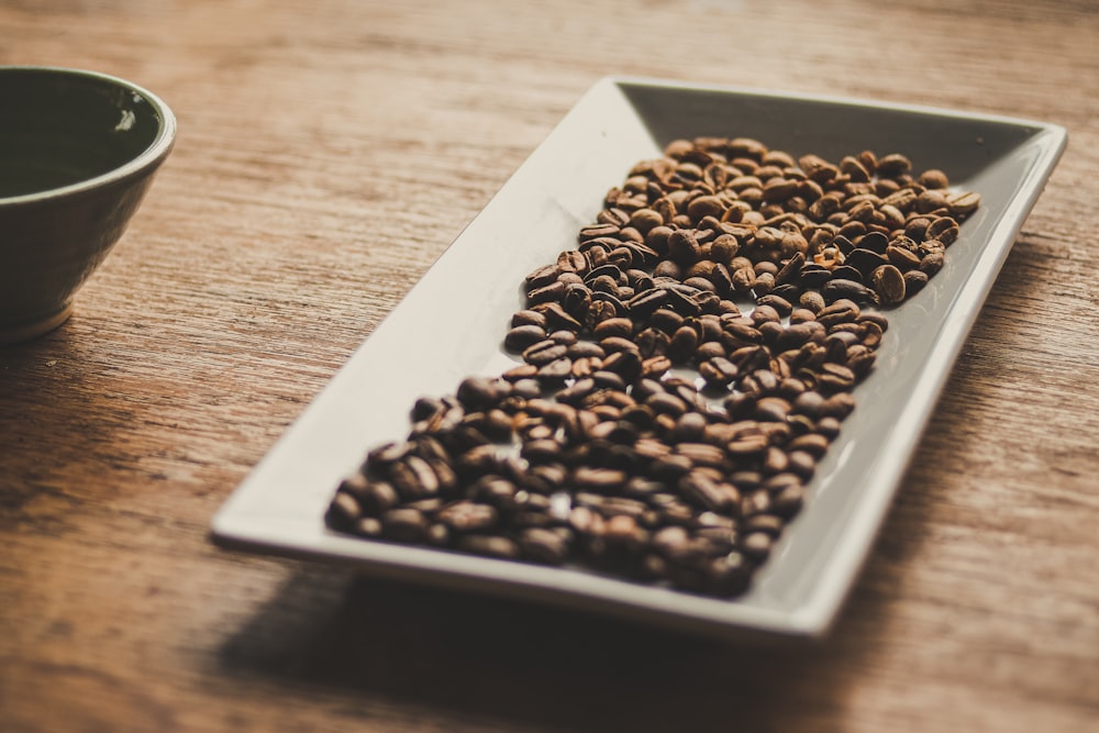 black and brown coffee beans on white ceramic tray