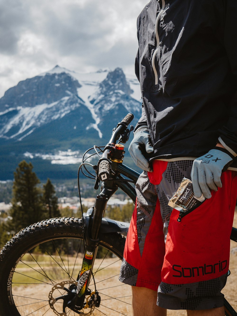 Mann in schwarzer Jacke und roter Hose fährt schwarzes Mountainbike