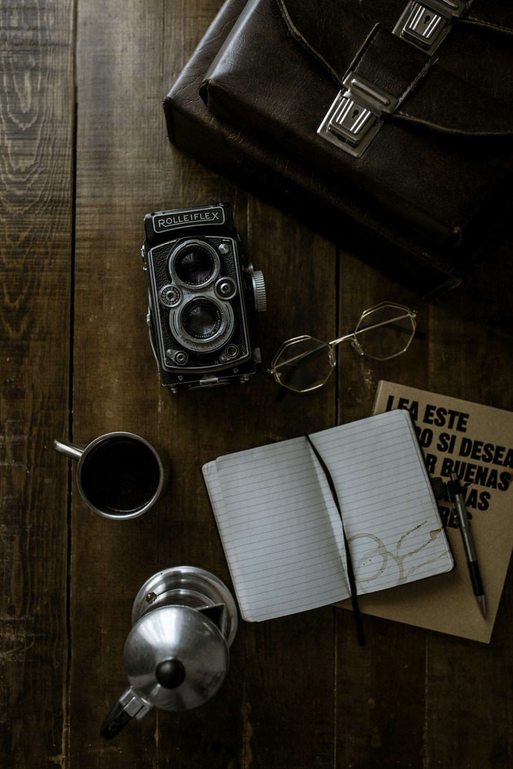 black nikon dslr camera beside white paper on brown wooden table
