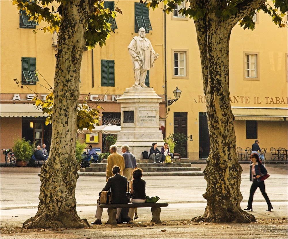 people sitting on bench near brown concrete building during daytime