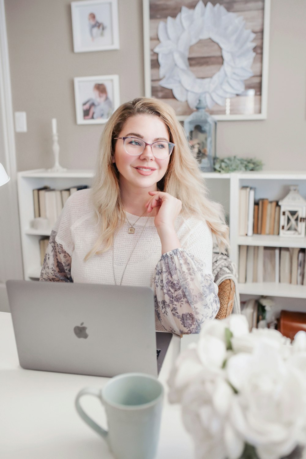 Donna in camicia a maniche lunghe in pizzo bianco utilizzando MacBook d'argento