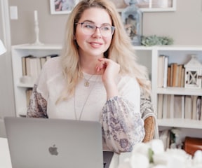 woman in white lace long sleeve shirt using silver macbook