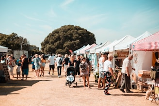 A vibrant marketplace scene showing diverse travelers sharing stories and smiles under a bright blue sky.