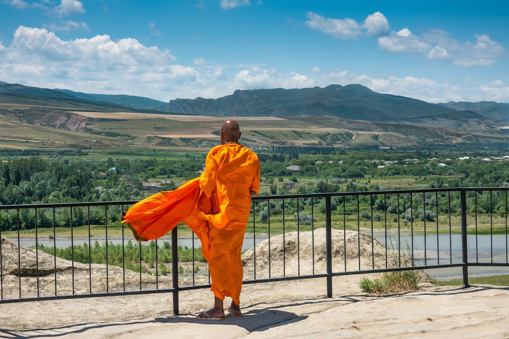 man in orange robe standing on gray concrete floor during daytime