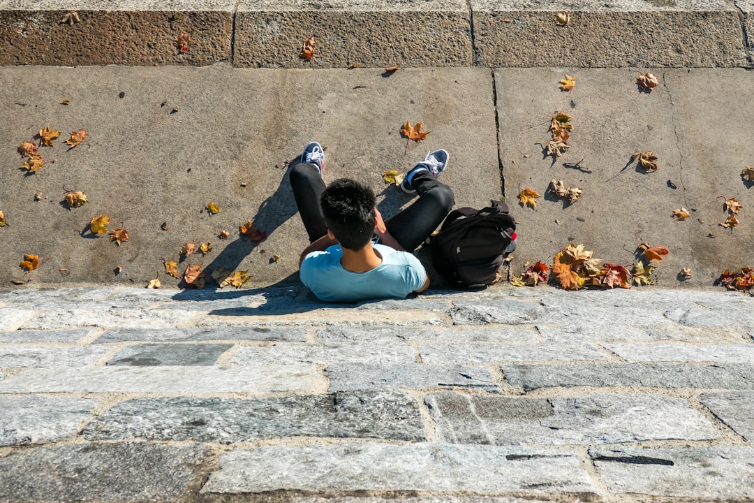 man in blue tank top and black pants lying on concrete floor