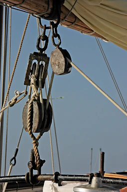 Close-up of a ship's capstan with ropes tightly wound around it on a sunny day.