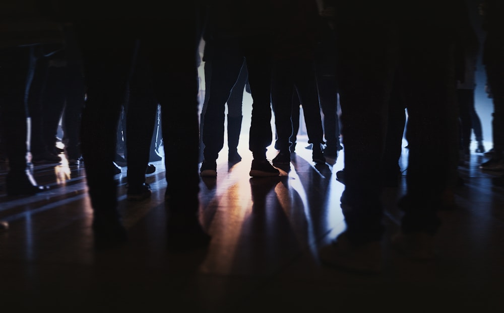 silhouette of people standing on brown wooden floor