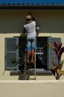 woman in white shirt and blue denim shorts standing on white and gray ladder during daytime