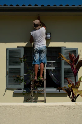 woman in white shirt and blue denim shorts standing on white and gray ladder during daytime