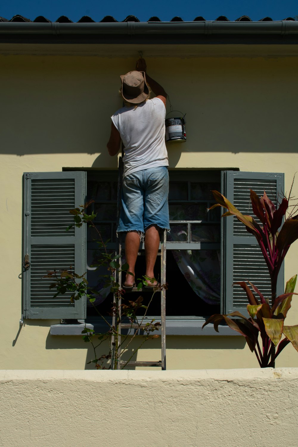 woman in white shirt and blue denim shorts standing on white and gray ladder during daytime