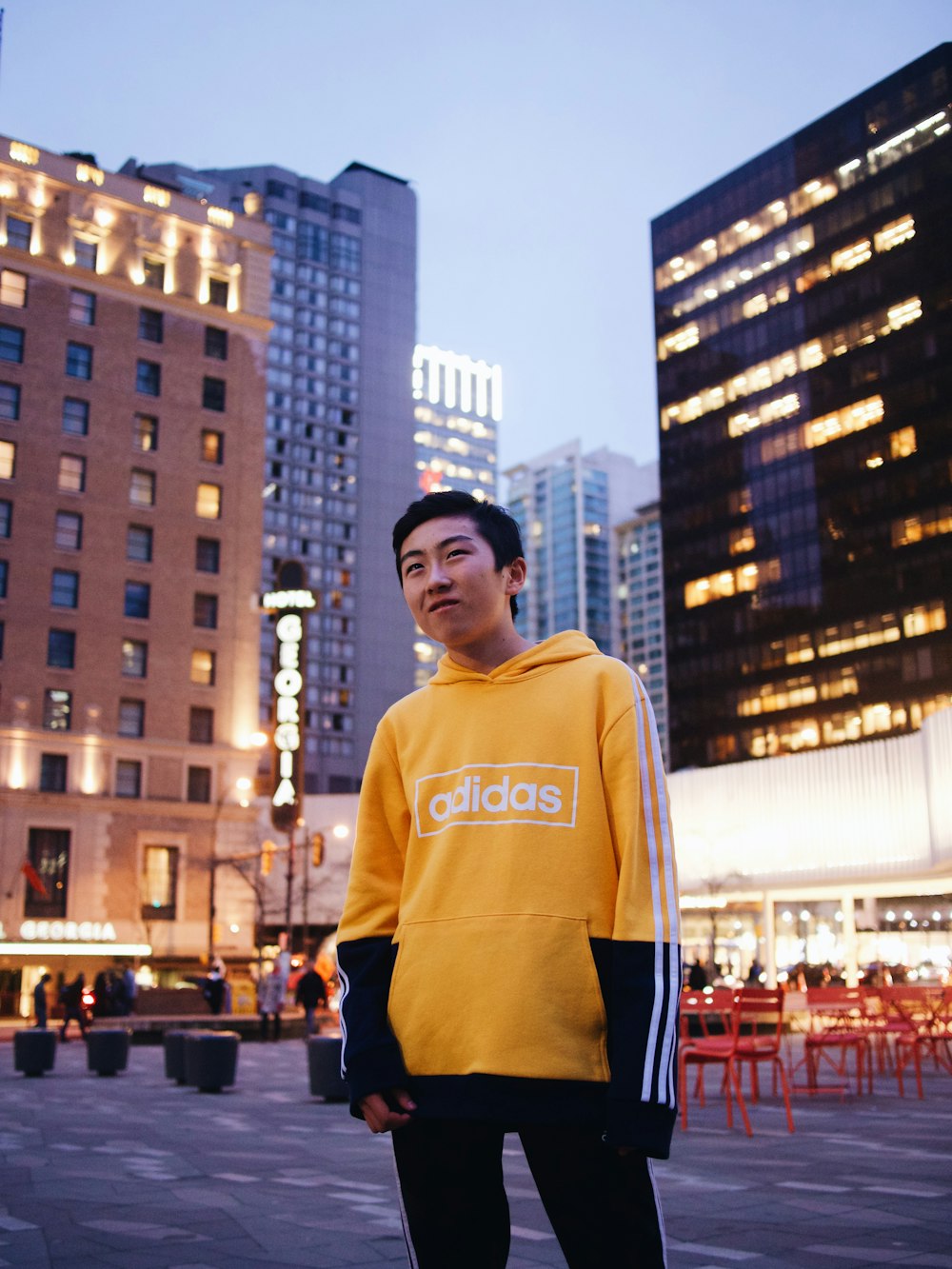 man in yellow hoodie standing on the street during daytime