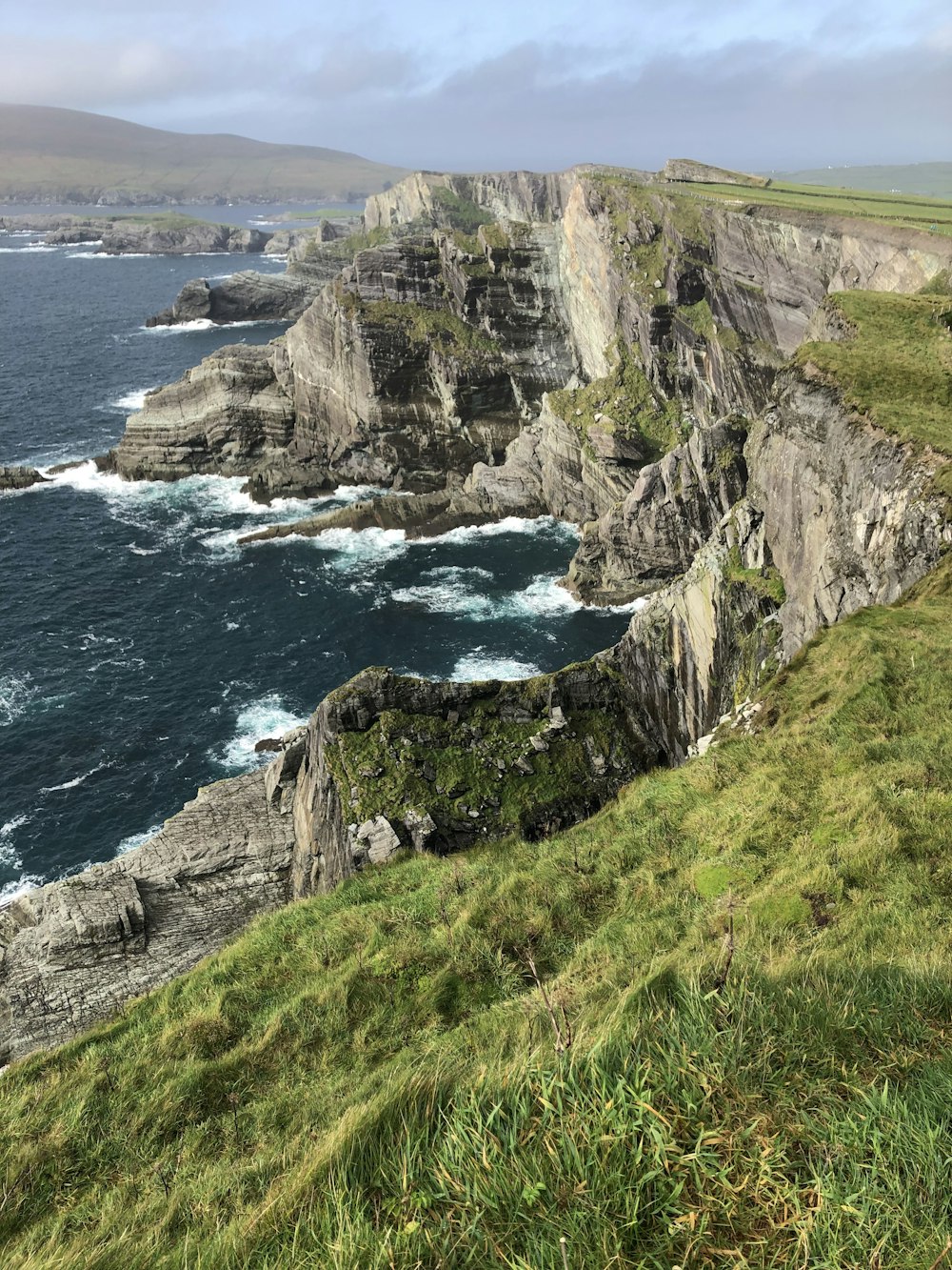 green grass on rocky mountain beside sea during daytime