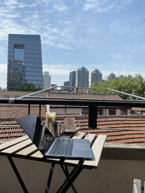 A serene morning scene with a journal, coffee, and a laptop on a balcony