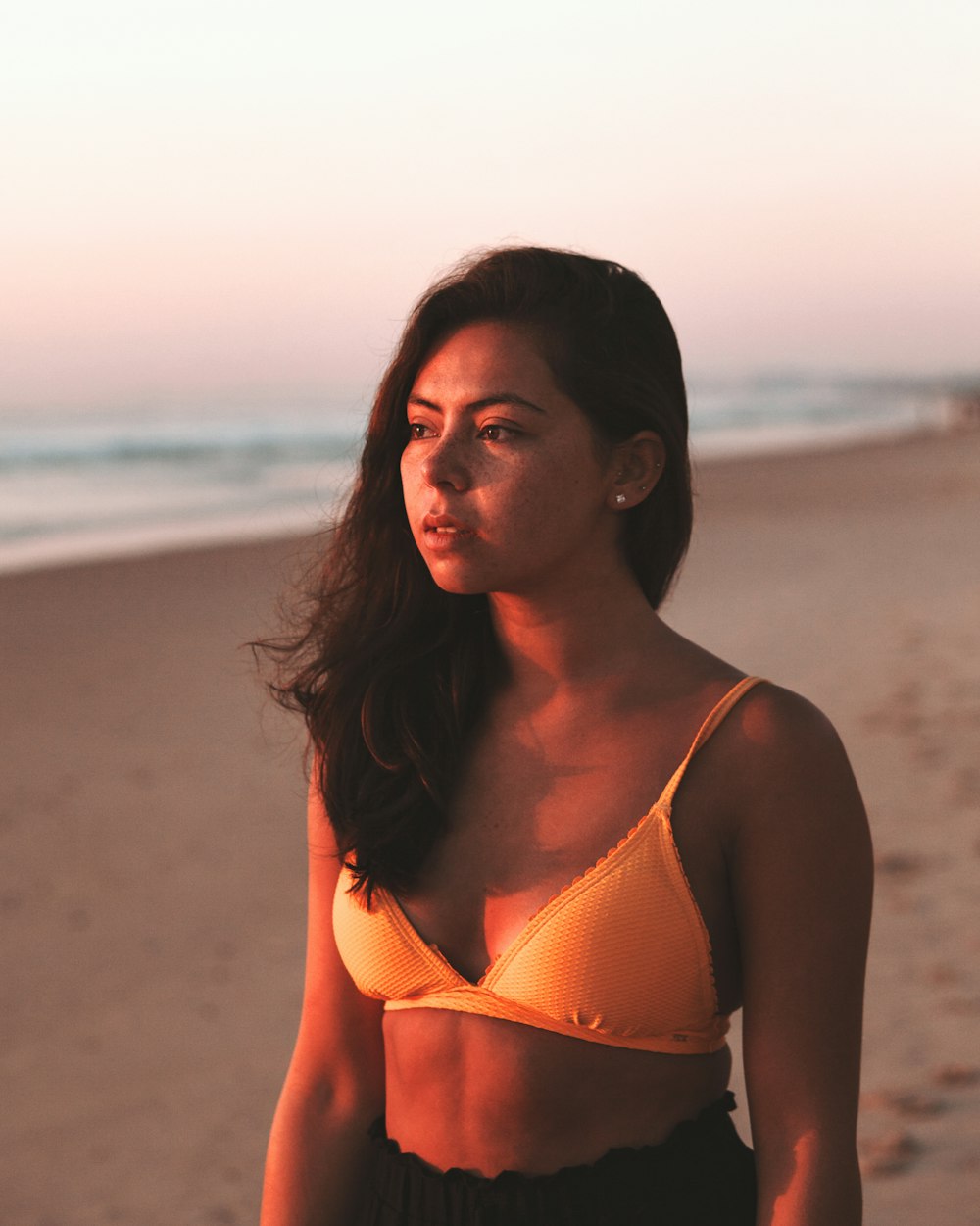 donna in bikini arancione top in piedi sulla spiaggia durante il giorno
