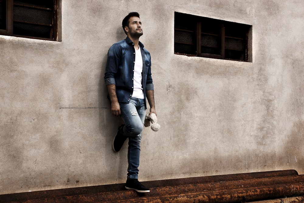 Foto Hombre con camisa de vestir azul y jeans de mezclilla azul de pie  junto a una pared de concreto gris durante el día – Imagen México gratis en  Unsplash