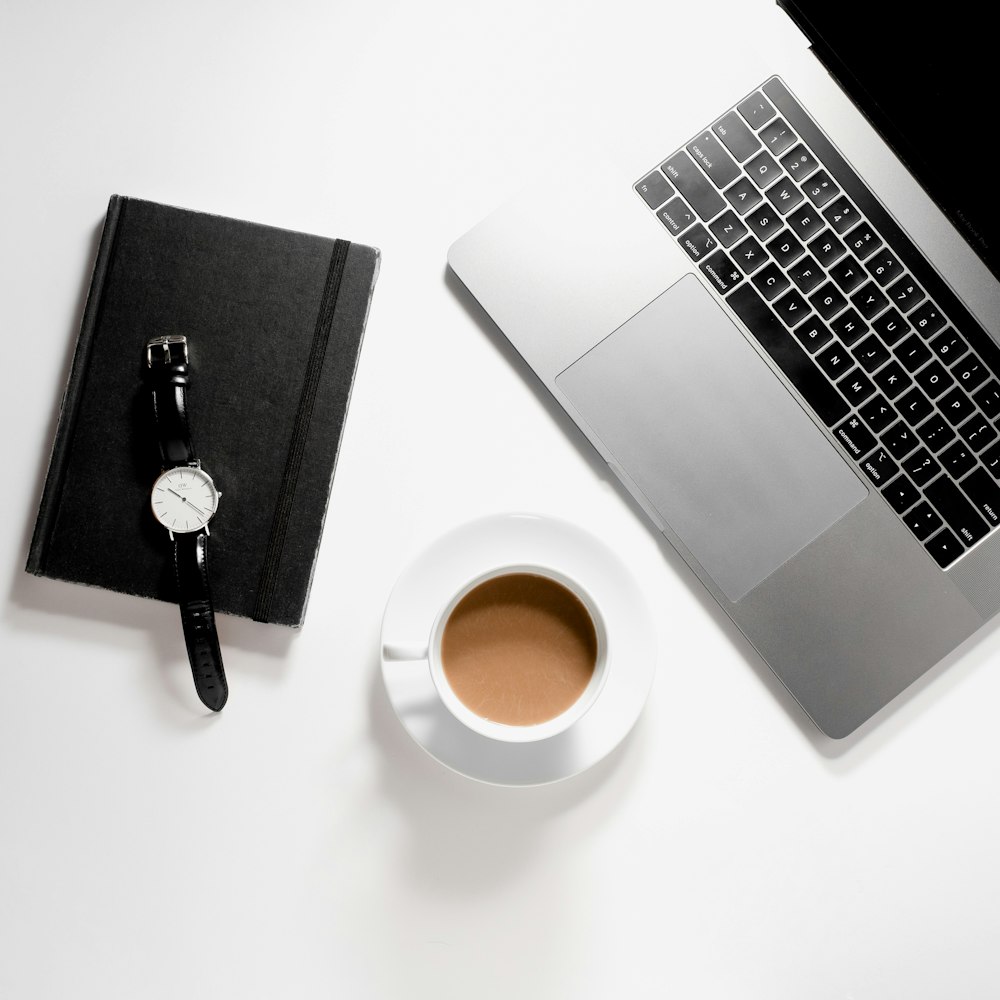 macbook pro beside black and silver pen and black round watch